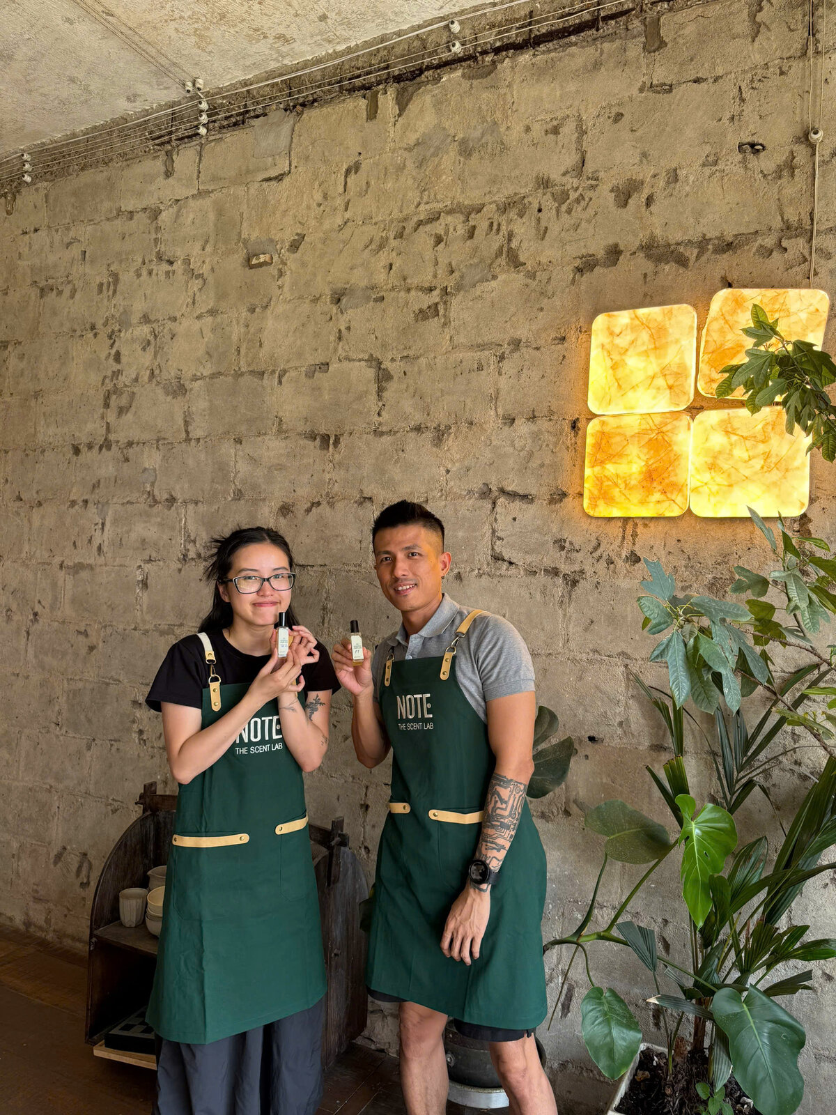 Happy travelers showing custom perfume bottles at NOTE workshop Cafe Apartment Saigon